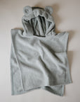 The mushie Bear Poncho Towel, made from organic cotton and featuring bear ears on the hood, is shown in light gray laid flat on a neutral background.