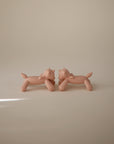 Two identical, minimalist, nude-colored mushie Unicorn Figurine Teether sculptures face each other on a plain, light beige background with soft lighting.