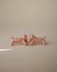 Two identical, minimalist, nude-colored mushie Unicorn Figurine Teether sculptures face each other on a plain, light beige background with soft lighting.