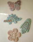 Set of 4 mushie Silicone Sensory Toys: butterfly, dinosaur, rocket, and flower.