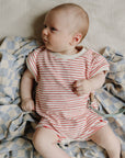 Baby in stripes with mushie Linen Pacifier Clip 2-Pack, silicone clasp, on the blanket.