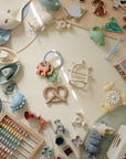 Mushie Teething Gift Set with pastel toys, puzzles & silicone teether on a cream surface.