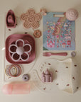 Collection of pink children's tableware and toys on a white surface