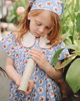 A young girl explores near green plants with a mushie Kaleidoscope.