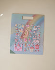 The mushie Reusable Sticker Set features pastel moon, stars, unicorns, castles, and hearts on a rainbow background. Shown on a light surface—great for fans of reusable or puffy stickers. Packaging reads "mushie Reusable Sticker Set.