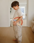 Young boy enjoys screen-free play with mushie's Wooden Magnetic Rainbow Maze indoors.