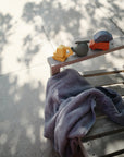 Mushie Mold Free Bath Play Set with food grade silicone toys on a sunlit wooden bench.