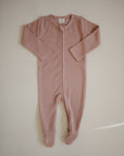 The mushie Zipper Pajama is a long-sleeved, footed baby sleepwear in soft dusty pink, laid flat on a light background. It features a front zipper from neck to leg for easy dressing and comfort.