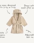 The mushie Bear Robe is a beige organic cotton kids' robe with a hood and bear ears, available in sizes 2-4y or 4-6y. It stays soft after washing and has an adjustable belt for a cozy fit.