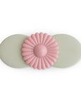 The mushie Suction Spinner Toy in Blossom features two overlapping ovals and a pink daisy design, made from food-grade silicone. "mushie" is embossed on the right oval, providing a gentle sensory experience.