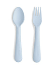 Mushie Dinnerware Fork and Spoon Set for children in powder blue, made from non-toxic plastic with smooth, rounded handles embossed with the mushie logo. Dishwasher-safe and shown on a white background.