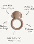 The mushie Dog Teether is a brown, dog-shaped silicone teether with a ring handle. Made from 100% food-grade, non-toxic silicone, it's BPA, BPS, PVC & phthalate free, dishwasher safe, and designed to help build fine motor skills.