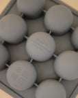 The Mushie Baby Food Freezer Tray is a gray, BPA-free silicone tray with nine round molds, made from 100% food grade silicone. It's perfect for baby food storage and features small safety and usage icons. Made in China.