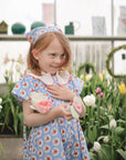 Young girl enjoys tulips while playing with mushie Suction Spinner Toy.