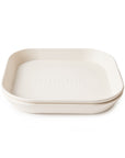 The mushie Square Dinnerware Plates are off-white, BPA-free silicone dishes with rounded corners and "mushie" embossed in the center—a stylish, safe addition to your baby plates or plastic dinnerware set.