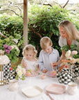 A woman and kids enjoy cake outdoors with mushie Square Dinnerware Plates.