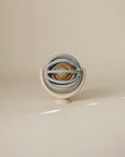 Suction spinner ball toy with stacked circular rings on a beige background