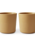 Two identical mushie Dinnerware Cups for kids, plain and light brown, are placed side by side on a white background.