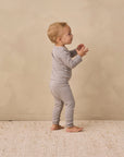 Toddler in Rylee + Cru Ribbed Tee + Legging Set Slate Microstripe stands on a beige rug.