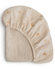 The mushie Extra Soft Bassinet Muslin Crib Sheet is a beige, breathable baby bedding with an elastic edge and a subtle brown rainbow pattern.