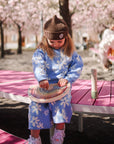 A young girl plays with the mushie Wooden Magnetic Rainbow Maze on a pink bench.
