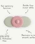 The mushie Suction Spinner Toy is a pastel flower-shaped spinner with two suction cups and a pink spinning center, designed for motor skill development, sensory engagement, safe materials, and secure attachment to smooth surfaces.