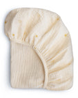 The mushie Extra Soft Bassinet Muslin Crib Sheet in cream features a subtle yellow sun design and elasticized edges, offering breathable bedding for your nursery.