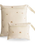 Set of two mushie Water Resistant Wet Bags in Rainbows color, featuring a beige design with simple brown rainbows. The larger bag has a side fabric handle and both have a small rectangular label at the bottom corner.