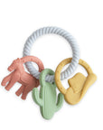 The mushie Western Teething Ring features a white, textured loop with three colorful, food grade silicone charms—a pink horse, green cactus, and yellow cowboy hat—creating a safe and fun sensory toy for babies.