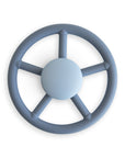 The mushie Suction Spinner Toy in Wheel color, made from food-grade silicone and shaped like a steering wheel with "mushie" at the center, provides a gentle sensory experience and is shown from above on a white background.