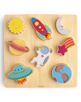 A wooden puzzle featuring colorful pieces shaped like the sun, rocket, moon, Saturn, shooting star, UFO, astronaut, and Earth, arranged on a light wood square board.