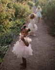 Young girls play barefoot; one drinks, holding a FRIGG Daisy Natural Rubber Pacifier.