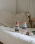 Two mushie Stacking Cups Toys on a bed, perfect for building baby motor skills and cozy play.