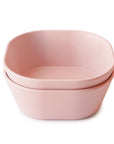 The mushie Square Dinnerware Bowls are two stackable, blush pink, square-shaped bowls with rounded corners, made from BPA-free plastic, shown against a white background.