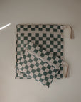 Two rectangular mushie Water Resistant Wet Bags with green and white check patterns and white zippers—one large, one small—each has a beige strap. They're perfect for organizing essentials or diaper bag storage.