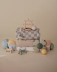 Mushie Extra Soft Muslin Crib Sheet and neutral baby toys displayed on a beige background.