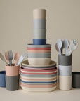 A tidy stack of mushie Dinnerware Cups in pastel, non-toxic plastic is neatly arranged against a neutral background, showcasing colorful kids cups organized in overlapping stacks.
