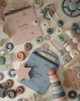 Mushie Reusable Water Color Pads and pastel baby toys arranged neatly on a light surface.