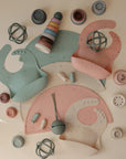 A flat lay of mushie silicone placemats in soft mint, pink, beige, and gray arranged neatly on a cream surface.