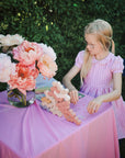 A girl sits at a small table outdoors, playing with mushie Wooden Balance Blocks and Fairies Reusable Sticker Set.