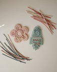 Two mushie Silicone Sensory Toys with colorful sticks, ideal for fine motor play on light surfaces.