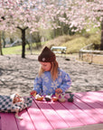 A child plays with toys near a mushie Water Resistant Wet Bag under cherry blossoms.