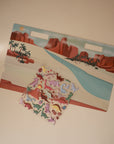 Pair the mushie Reusable Sticker Set with a vibrant playset featuring a desert backdrop, red rocks, river, palm trees, and dinosaur toys—ideal for sparking creativity and imaginative play.