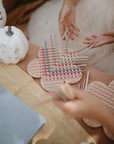 Kids love fine motor play with mushie Silicone Sensory Toy in pastel colors by white pumpkins.