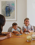 A woman and two kids play with a mushie Silicone Sensory Toy at a table in a modern room.