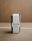 Two stacked gray mushie Dinnerware Cups with a white label rest on a brown minimalist surface—non-toxic, dishwasher safe, made in Denmark. Ideal for kids and blending Scandinavian style with everyday safety.