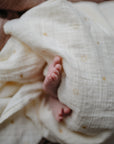 Lifestyle image of a baby swaddled in organic cotton swaddle in Suns