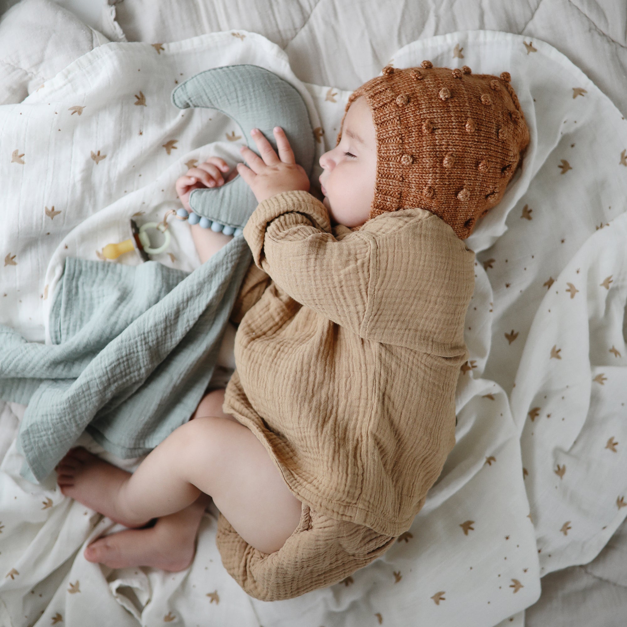 Lifestyle image of a baby swaddled in organic cotton swaddle in Sparrow