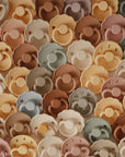 FRIGG Daisy Silicone Pacifier 2-Pack by FRIGG features scalloped silicone pacifiers in soft earthy tones—beige, brown, tan, mustard, and sage—arranged together for baby comfort.