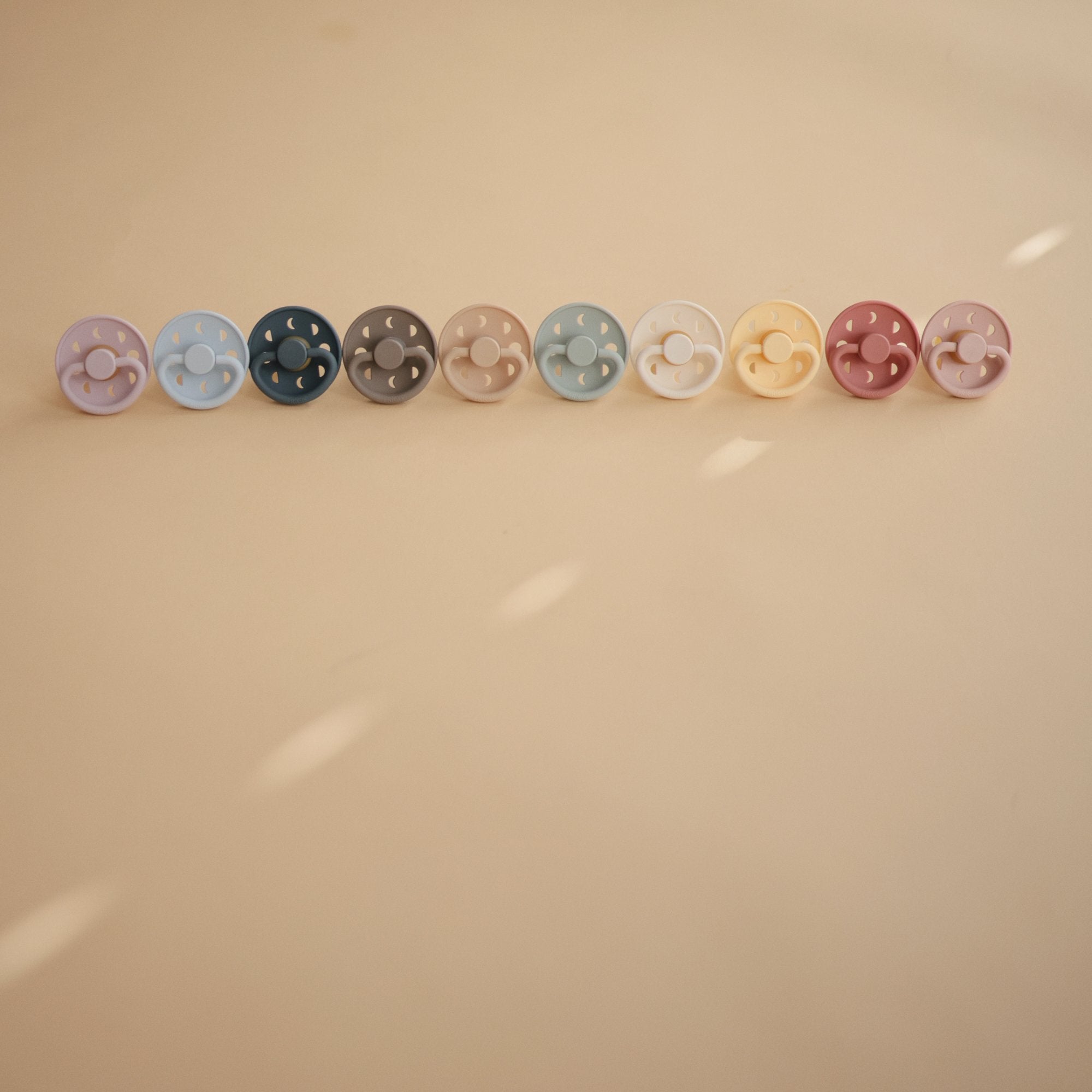 Lifestyle image Moon Silicone Frigg pacifiers all in a row.